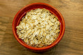 Rolled oats in a red bowl on a wooden table